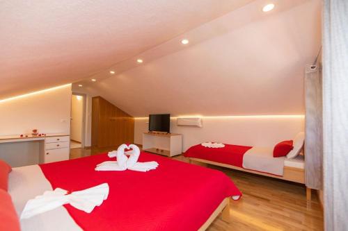a bedroom with two beds with red and white sheets at Apartman Dinko in Bol