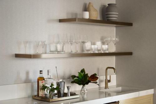 a kitchen counter with glasses on shelves and a sink at InterContinental Indianapolis by IHG in Indianapolis