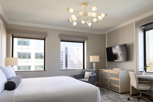 a bedroom with a bed and a desk and windows at InterContinental Indianapolis by IHG in Indianapolis