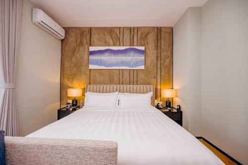 a bedroom with a large white bed and two lamps at Pan Pacific Serviced Suites Nairobi in Nairobi