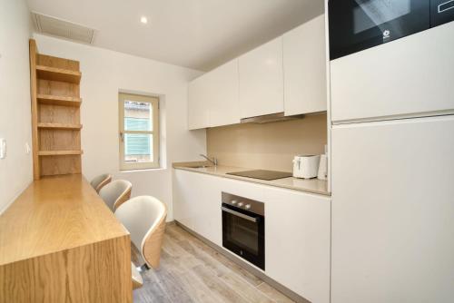 - une cuisine avec des placards blancs, une table et un réfrigérateur dans l'établissement Elegant apartment-AC-1BR-2P- center Saint-Tropez, à Saint-Tropez