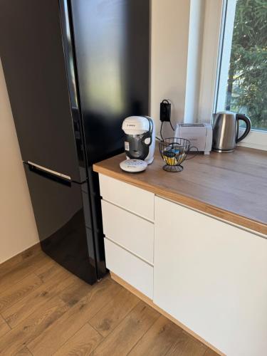 a kitchen with a black refrigerator and white cabinets at Dom-na Mazury! in Mrągowo