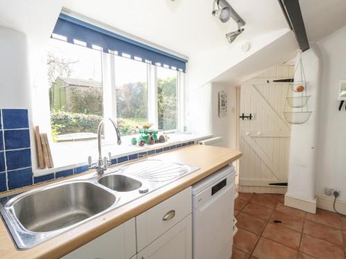 eine Küche mit Spüle und Fenster in der Unterkunft Cobblers Cottage in Weymouth