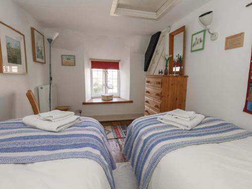1 Schlafzimmer mit 2 Betten, einer Kommode und einem Fenster in der Unterkunft Cobblers Cottage in Weymouth