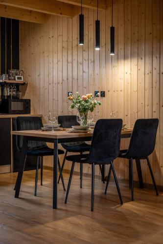 a dining room table with chairs and a vase of flowers at Złota Palma Kopań -domki całoroczne nad morzem in Kopań