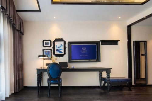 a desk with a television on a wall with a chair at LanOu hotel in Chengdu