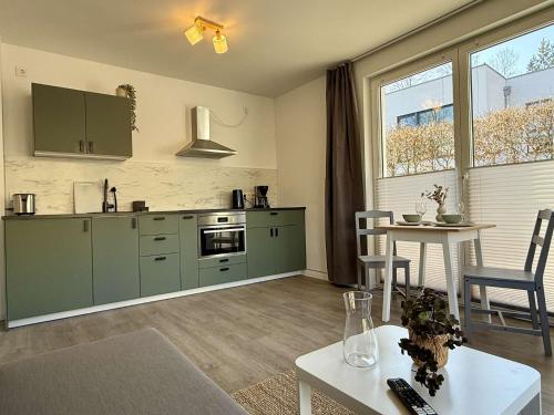 a kitchen with green cabinets and a table in a room at MontiRooms- Apartment nahe Berlin & Natur in Woltersdorf