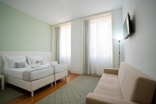 a living room with a white bed and a couch at Turista Da Trindade in Porto
