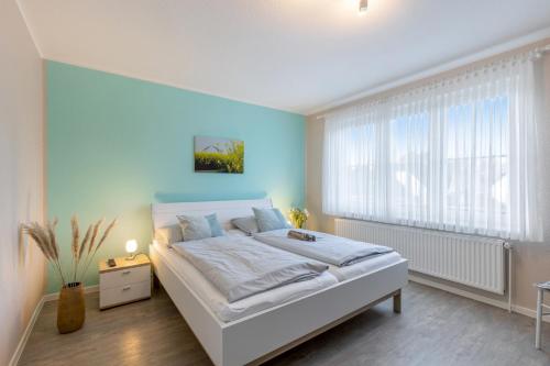 a bedroom with a white bed and a blue wall at Ferienhaus Rose in Fehmarn