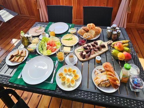 a table topped with plates of food and fruit at Rajska polana Domki PREMIUM ,na odludziu z prywatną BALIĄ z jacuzzi i sauną ,Cisza,rowery elektryczne,góry,astroprzygoda,- Adršpach, Skalne Miasto, Zamek Książ,Andrzejówka,Karpacz, Śnieżka,Janskie Laznie,Pec in Mieroszów