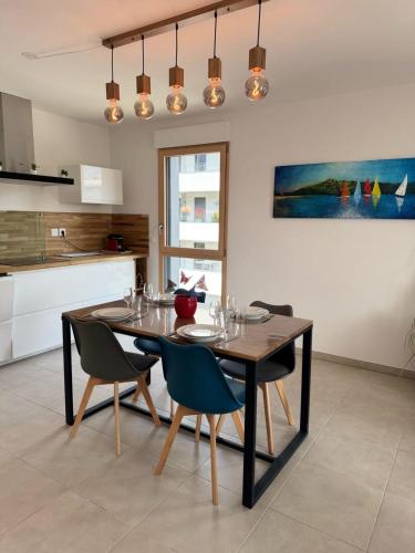 une salle à manger avec une table et des chaises et une cuisine dans l'établissement La parenthèse du lac - Lake view and private parking, à Aix-les-Bains