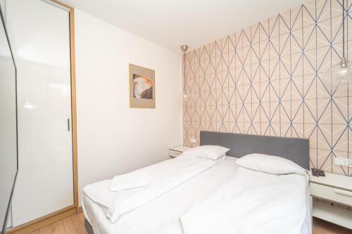 a bedroom with a white bed and a wall at Comfortable 3city Studios in Sopot by Noclegi Renters in Sopot