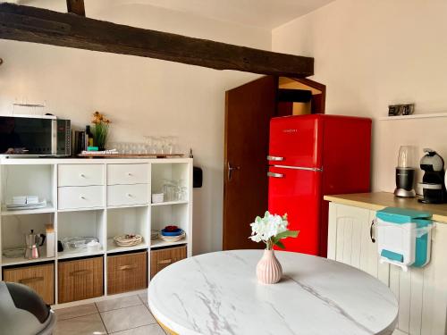 une cuisine avec une table et un réfrigérateur rouge dans l'établissement Paloma, à Figeac