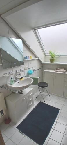 a bathroom with a sink and a mirror and a chair at Ferienwohnung am Schwarzwaldrand in Nagold