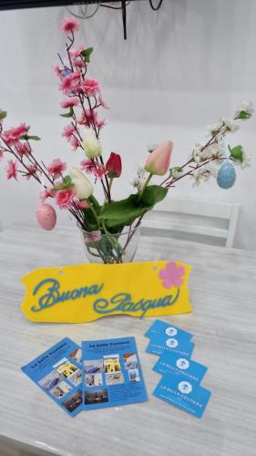 a vase filled with flowers and a card and a banner at La bella costiera home in Sant'Egidio del Monte Albino