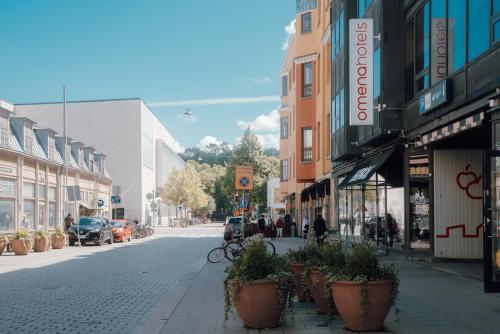 a city street with potted plants on the sidewalk at Omena Hotel Turku Kauppiaskatu in Turku