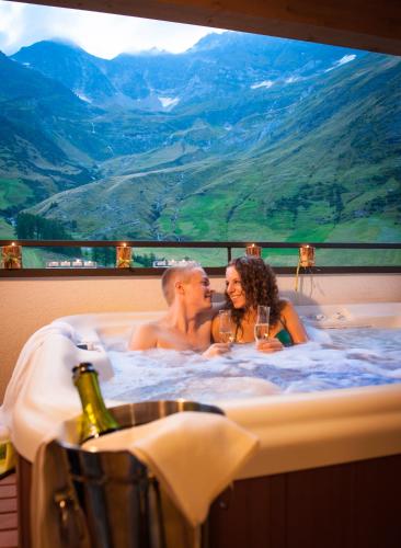 a man and woman sitting in a bath tub with wine glasses at Montresor Hotel Pfeldererhof in Pfelders
