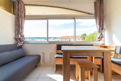 Cette chambre comprend une table, un canapé et une fenêtre. dans l'établissement Vue lac & mer à pied - Séjour détente, à Port-la-Nouvelle