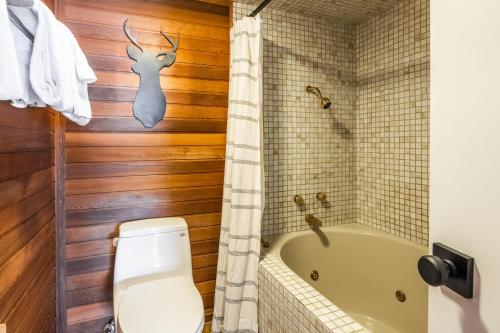 a bathroom with a toilet and a tub with a deer head on the wall at Cedar and Snow in Mammoth Lakes