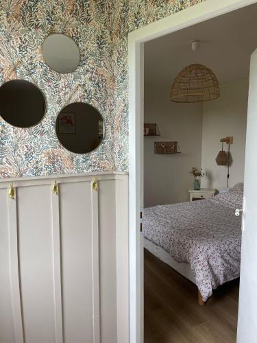 une chambre avec un lit et deux miroirs au mur dans l'établissement Maisonnette de charme, à Quemper-Guézennec