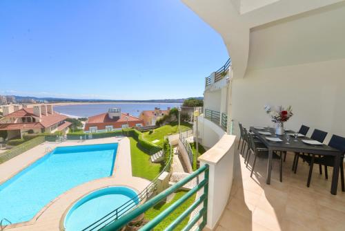 a balcony with a swimming pool and a dining table at Bay in São Martinho do Porto