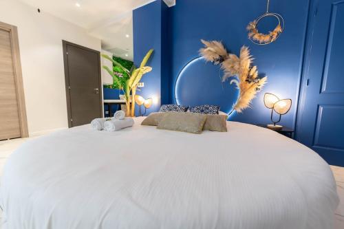 Cette chambre comprend un grand lit blanc et un mur bleu. dans l'établissement Chambre avec Balnéo, centre ville de Nice, à Nice