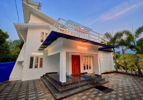 a white house with a red door and stairs at Cool Nest 5 BR Pool Villa Munnar by VOYE HOMES in Munnar