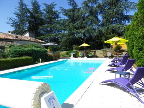 une piscine avec chaises et parasols dans l'établissement Villa Luxe avec Spa, Piscine Chauffée & Salle de Sport à Beauville, à Beauville