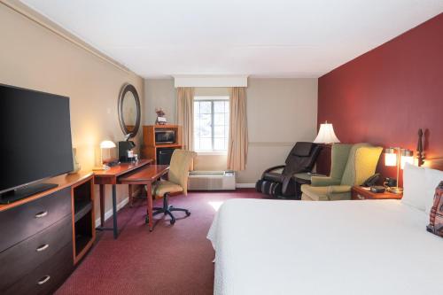 a hotel room with a bed and a desk with a television at Fireside Inn & Suites West Lebanon in West Lebanon