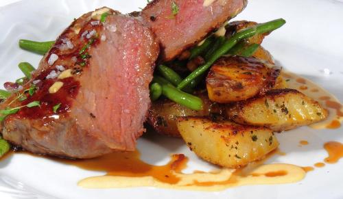 a plate of food with meat potatoes and green beans at Park Hotel Pruhonice in Pruhonice