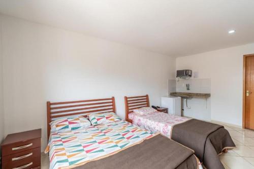 a bedroom with two beds and a refrigerator at OYO Residencial Muriqui Apart Hotel, Mangaratiba in Vila Muriqui