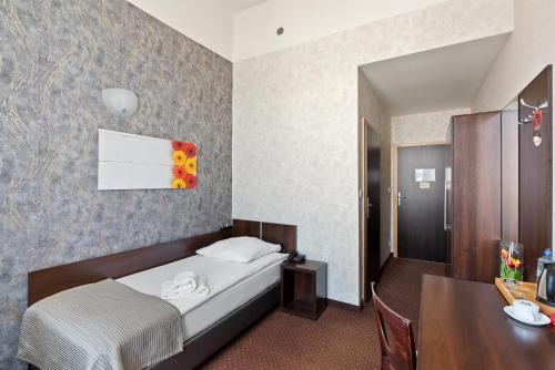 a bedroom with a bed and a desk and a table at Hotel Diament Economy Gliwice in Gliwice