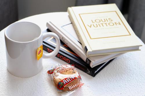 a pile of books on a table with a coffee mug at Leo's Beach Haven in Batehaven
