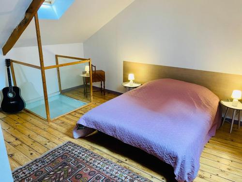 - une chambre avec un lit, deux tables et une guitare dans l'établissement La maison du Cordonnier, à Gouesnou