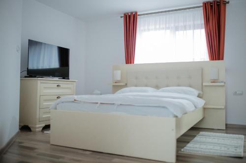 a white bedroom with a large bed and a television at Boierița Home Stay in Fundu Moldovei