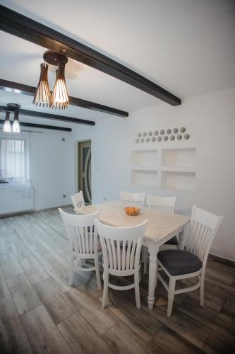 a dining room with a table and white chairs at Boierița Home Stay in Fundu Moldovei