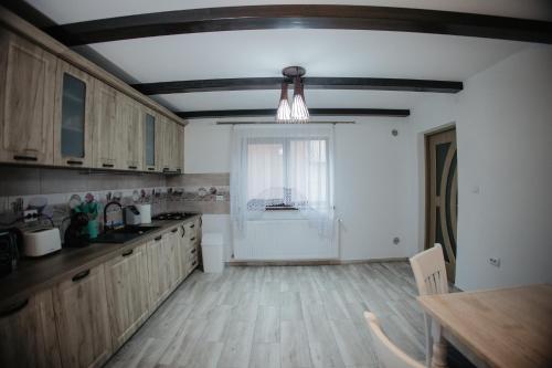 a kitchen with wooden cabinets and a table and a window at Boierița Home Stay in Fundu Moldovei