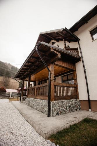 a building with a wooden porch on the side of it at Boierița Home Stay in Fundu Moldovei