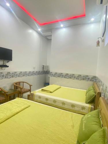 a room with two beds and a tv on the wall at Nhà nghỉ Bá Thành - Lý Sơn in Quang Ngai