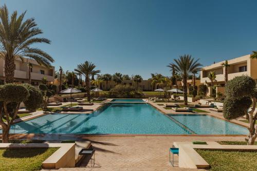 a large swimming pool with palm trees and buildings at Sirayane Boutique Hotel & Spa Marrakech in Marrakesh