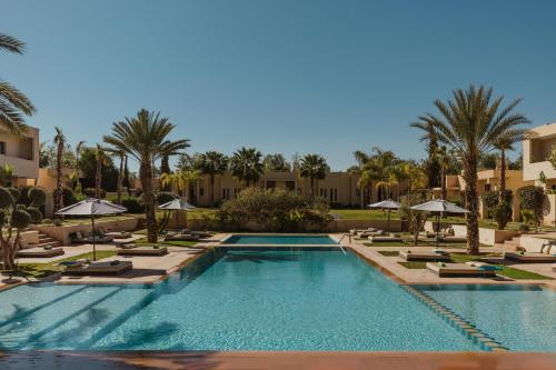 a pool with chairs and umbrellas in a resort at Sirayane Boutique Hotel & Spa Marrakech in Marrakesh