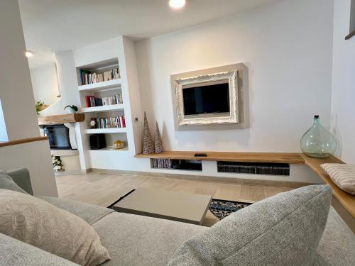 a living room with a couch and a tv on a wall at Villa Laura in Pietra Ligure