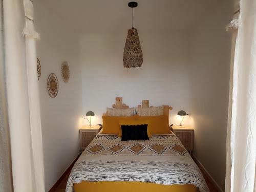 a bedroom with a bed with a yellow bedspread and two lamps at La petite maison à la campagne ! in Parcé-sur-Sarthe
