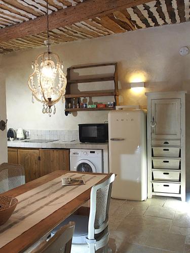 une cuisine avec une table et un réfrigérateur blanc dans l'établissement Le LOFT LOURMARIN, à Lourmarin
