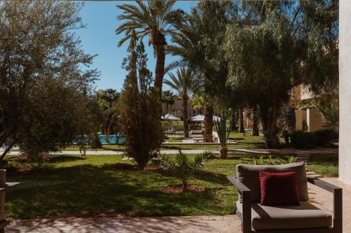 a couch sitting in a park with palm trees at Sirayane Boutique Hotel & Spa Marrakech in Marrakesh