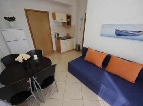 Una sala de estar con un sofá azul y una mesa. en Apartments Katija, en Baška Voda