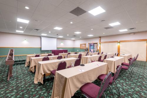 a conference room with tables and chairs and a screen at Fireside Inn & Suites West Lebanon in West Lebanon
