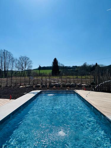 une piscine avec de l'eau bleue dans une cour dans l'établissement Le domaine d Isa piscine et Spa, à Vienville