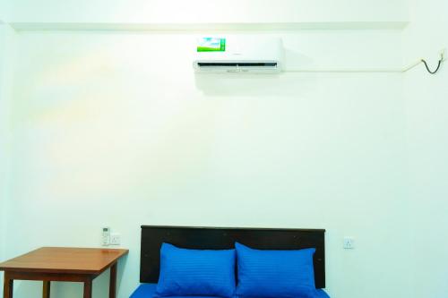 a bedroom with a bed with blue pillows and a table at TJ JANSE guest inn in Trincomalee