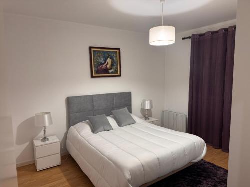 a bedroom with a large white bed and a painting on the wall at Moradia alegre no centro da Vila da Tocha. in Tocha